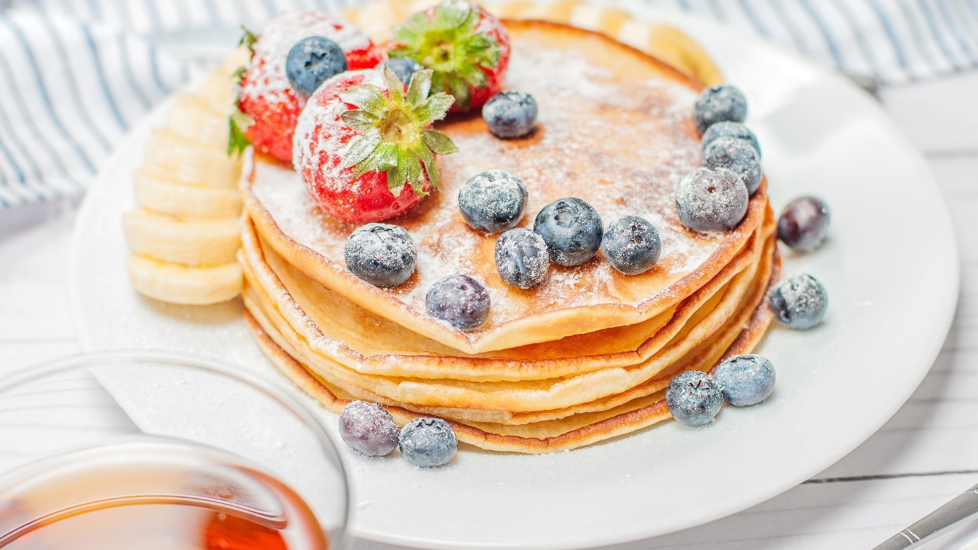 pancakes topped with berries and dusted with icing sugar